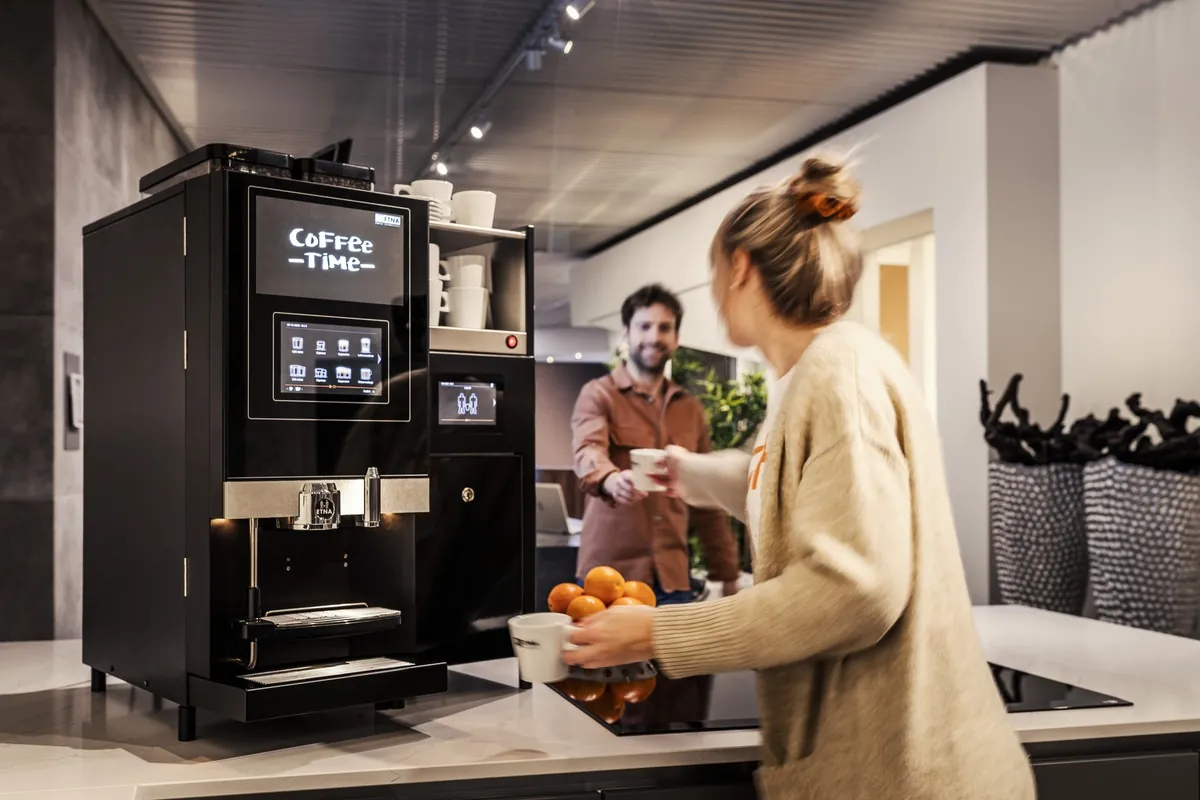 Twee collega's halen koffie aan de volautomaat op kantoor