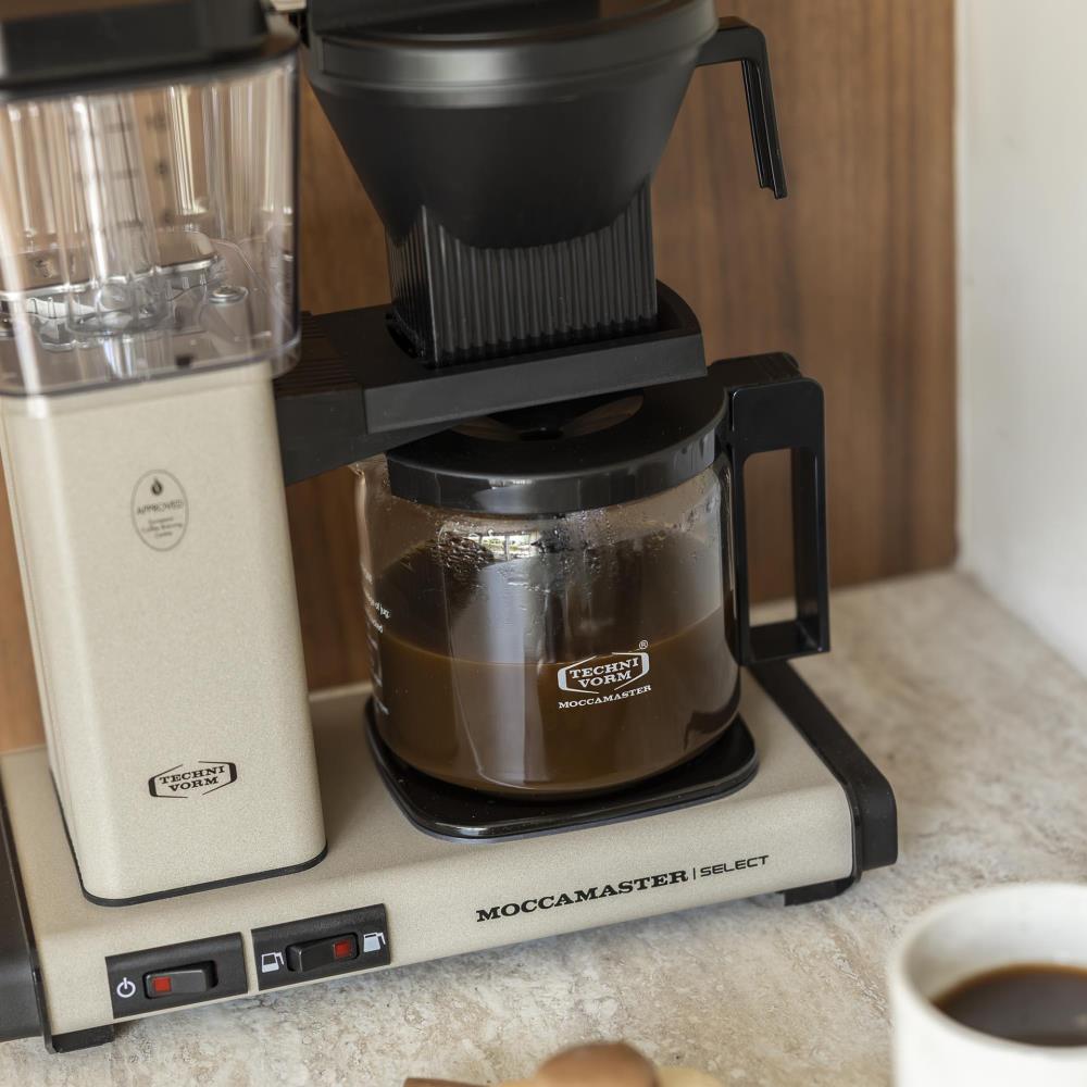 De KBG Select in Sandstone met een volle glaskan verse koffie